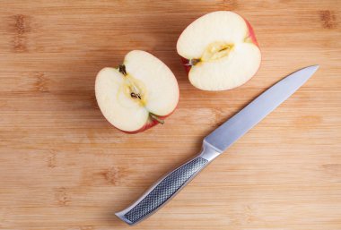 Ahşap kesme tahtası üzerinde bıçak ve kesilmiş elma. Elma dilim içine metal bir bıçak ile kesmek. Üstten Görünüm