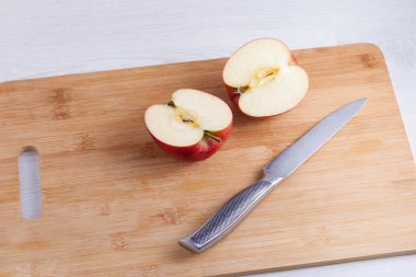 Ahşap kesme tahtası üzerinde bıçak ve kesilmiş elma. Elma dilim içine metal bir bıçak ile kesmek.