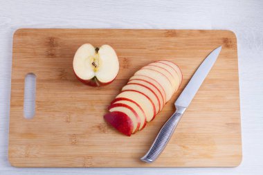 Ahşap kesme tahtası üzerinde bıçak ve kesilmiş elma. Elma dilim içine metal bir bıçak ile kesmek.
