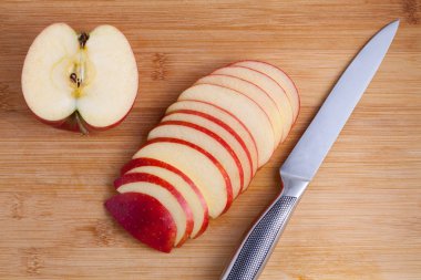 Ahşap kesme tahtası üzerinde bıçak ve kesilmiş elma. Elma dilim içine metal bir bıçak ile kesmek. Üstten Görünüm