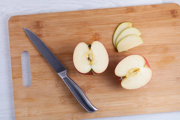 Knife and cut apples on a wooden cutting board. Apples cut into slices with a metal knife