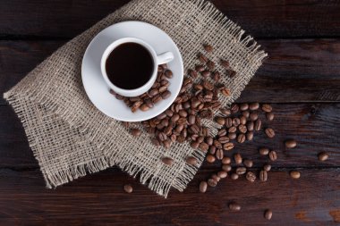 Beyaz fincan kahve kahve tahıllar koyu antika arka plan üzerinde keten kumaş ile. Üstten Görünüm.