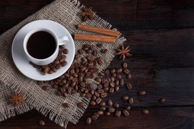 Beyaz fincan kahve kahve tahıllar koyu antika arka plan üzerinde keten kumaş ile. Üstten Görünüm.