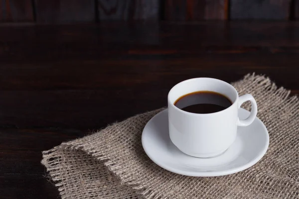Xícara branca de café em tecido de linho no fundo escuro do vintage — Fotografia de Stock