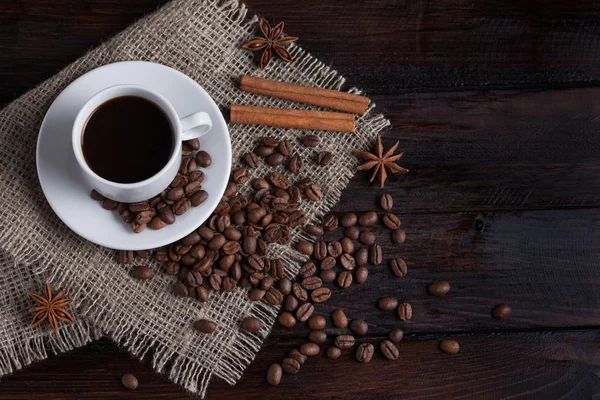 Beyaz fincan kahve kahve tahıllar koyu antika arka plan üzerinde keten kumaş ile. Üstten Görünüm.