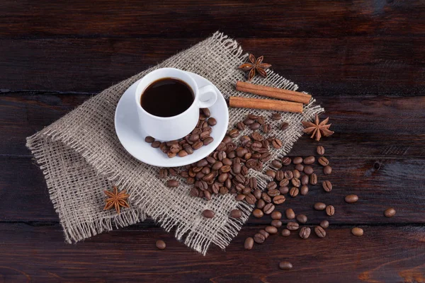 Ceașcă albă de cafea cu boabe de cafea lângă țesătura de in pe fundalul întunecat de epocă — Fotografie, imagine de stoc