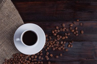 Beyaz fincan kahve kahve tahıllar koyu antika arka plan üzerinde keten kumaş ile. Üstten Görünüm