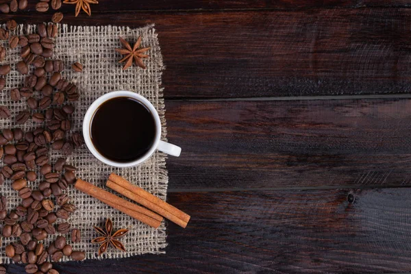 Ceașcă albă de cafea cu boabe de cafea lângă țesătura de in pe fundalul întunecat de epocă. Privire de sus — Fotografie, imagine de stoc