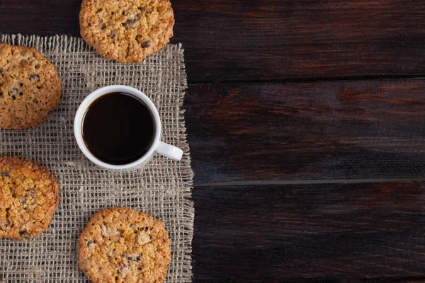 一杯美味的咖啡和饼干。早餐在深色木制背景与亚麻布。照片顶部视图 — 图库照片