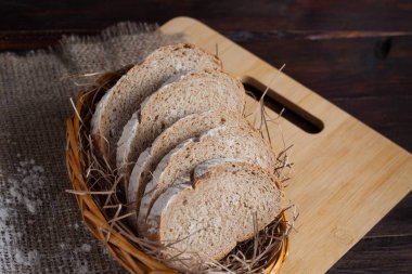 Taze adet hasır ile bir kase keten kumaş içinde meşe panosunda dağınık un bir ahşap zemin üzerine dilimlenmiş. Fotoğraf Üstten Görünüm