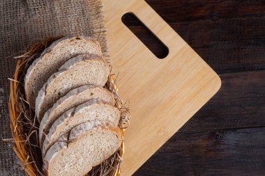 Taze adet hasır ile bir kase keten kumaş içinde meşe panosunda dağınık un bir ahşap zemin üzerine dilimlenmiş. Fotoğraf Üstten Görünüm