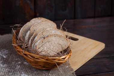 Taze adet hasır ile bir kase keten kumaş içinde meşe panosunda dağınık un bir ahşap zemin üzerine dilimlenmiş. Fotoğraf Üstten Görünüm