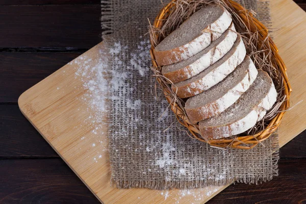 Potongan baru diiris dalam mangkuk wicker di papan ek dengan tepung tersebar di latar belakang kayu dengan kain linen. Tampilan puncak foto . — Stok Foto