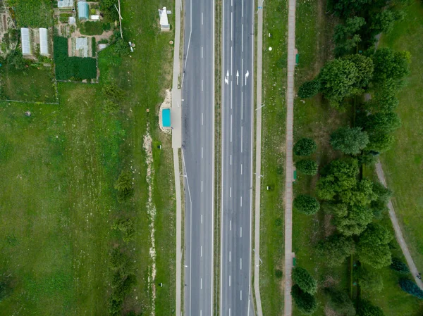 トップビューアスファルト道路、高速道路、明るい晴れた日に村の交差点。緑の森、草と航空写真 — ストック写真