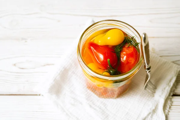 Tomat bermarinasi dalam toples kaca terbuka, garpu pada latar belakang kayu putih. Citra horisontal dengan ruang fotokopi — Stok Foto