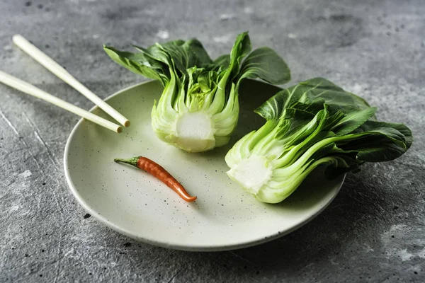 Baby Bok Choi Hälften auf einem Teller auf grauem Hintergrund — Stockfoto