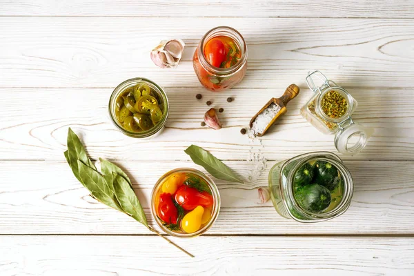 Conservas vegetales en frascos de vidrio, ingredientes de cocina sobre fondo de madera blanca, vista superior. Orientación horizontal . — Foto de Stock