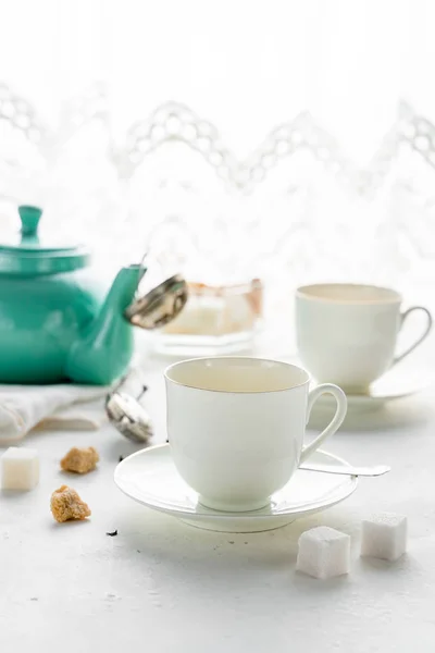 Teal gekleurde theepot, twee witte thee bekers, suikerpot op een tafel per venster. Afbeelding heeft Kopieer ruimte — Stockfoto