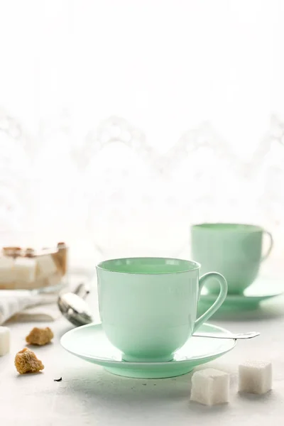 Mint gekleurde thee bekers, suikerpot op een tafel door venster — Stockfoto