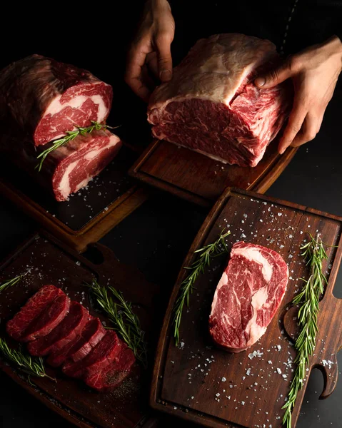 Carniceiro mostrando diferentes cortes de carne crua. Imagem chave baixa, orientação vertical . — Fotografia de Stock
