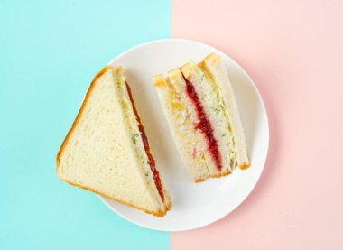 Trendy Kore sandviç inkigayo iki renkli pastel arka plan üzerinde bir tabak üzerinde, üst görünümü.