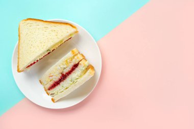 Trendy Kore sandviç inkigayo iki renkli pastel arka plan üzerinde bir tabak üzerinde, üst görünümü.