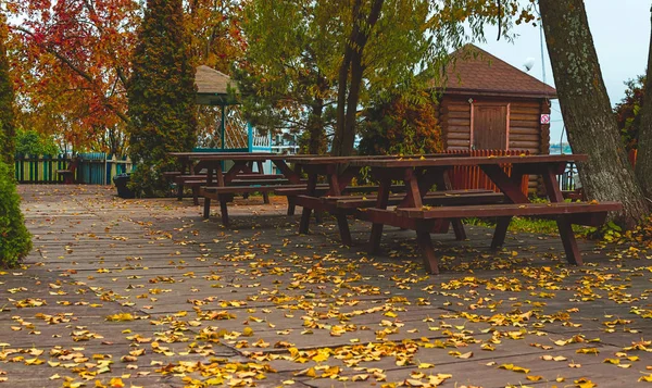 Wooden cabin, outdoor tables and behches in recreation area closed after summer. Autumn season.