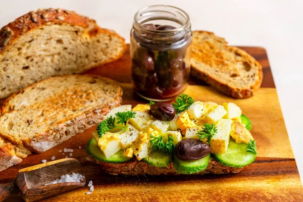Sanduíche aberto com salada de batata tradicional alemã, pão, azeitonas em tábua de corte de madeira — Fotografia de Stock
