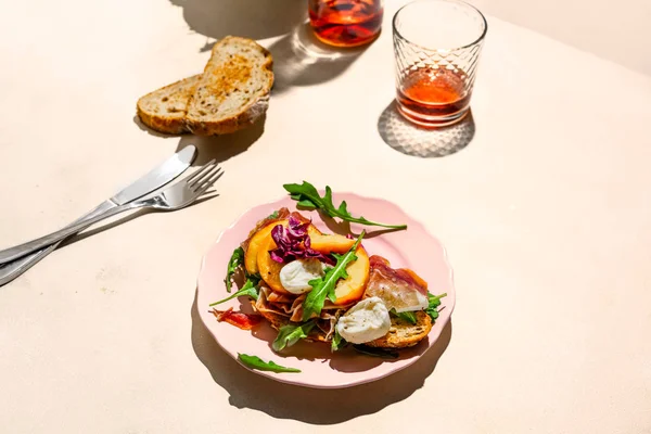 Presunto de Parma, mussarela e sanduíche de pêssegos em um prato, um pouco de pão e rosa tiro de vinho com luz dura — Fotografia de Stock