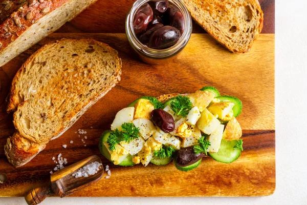 Sanduíche aberto com salada de batata tradicional alemã, pão, azeitonas em tábua de corte de madeira — Fotografia de Stock