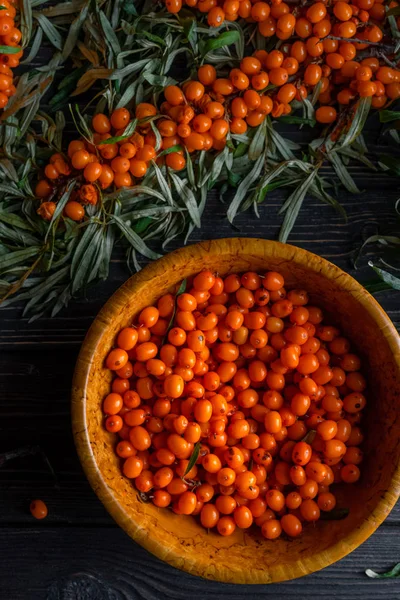 Blick auf Beeren und Sanddornzweige auf dunklem Holzgrund — kostenloses Stockfoto