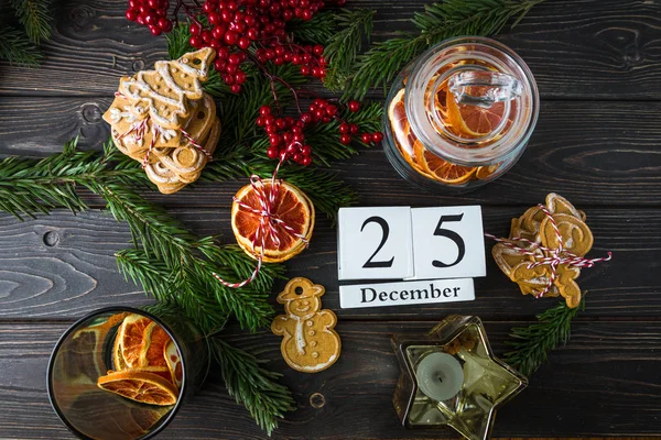 Calendario de madera con fecha 25 de diciembre, decoración navideña, chips de naranja, galletas de jengibre sobre fondo de madera, vista superior — Foto de Stock