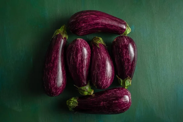 Gestreifte lila Auberginen auf dunkelgrünem Hintergrund — Stockfoto