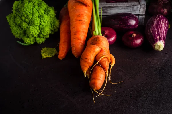 Berbagai sayuran segar termasuk wortel dengan puncak, terong, kubis romanesco dengan latar belakang gelap — Stok Foto