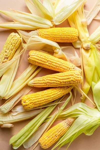 Heap of ripe yellow corn cobs with leaves on pastel pink background, closeup view — Free Stock Photo