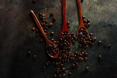 Üç tahta kaşık dolusu kopi luwak kahve çekirdeği.