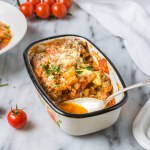 Zelfgemaakte groentecasserol en verse tomaten op een marmeren ondergrond