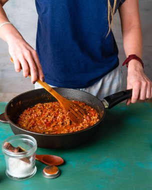 Kızartma tavasında soslu kıymayı karıştıran kadın. 