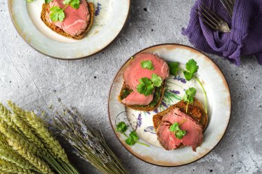 Etli sandviçler ve tabakta otlar.