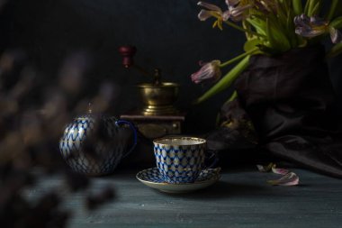 Ahşap arka planda bir fincan kahve ve çiçekler.