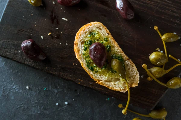 Koyu arkaplanda zeytinli ve kaparili taze ekmek