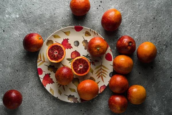 red sicilian oranges on a colorful plate on concrete background.