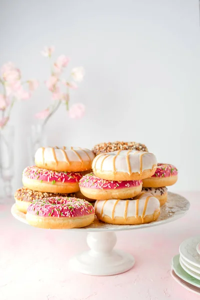 Assorted glazed doughnuts on a pink background