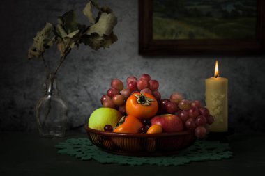 meyve sepeti ve mum masada.