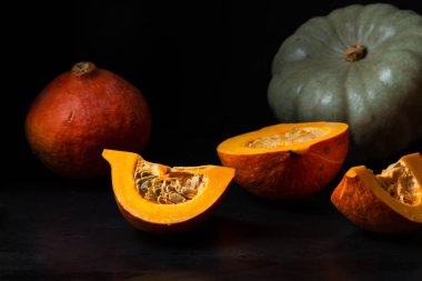 Tüm ve dilimlenmiş balkabakları koyu arkaplanda