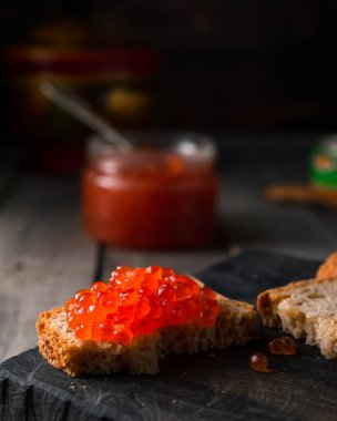 Çavdar ekmeğine kırmızı havyar, ahşap arka planda.