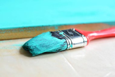 Taze boyanmış mavi ahşap, kırmızı saplı boya fırçası.