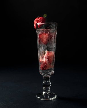 Kokteylli cam ve siyah arka planda çilek.