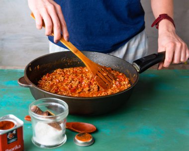 Kızartma tavasında soslu kıymayı karıştıran kadın. 