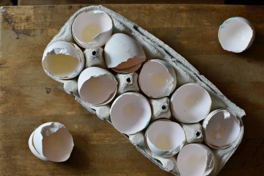 A carton box of empty egg shells on a wooden background 